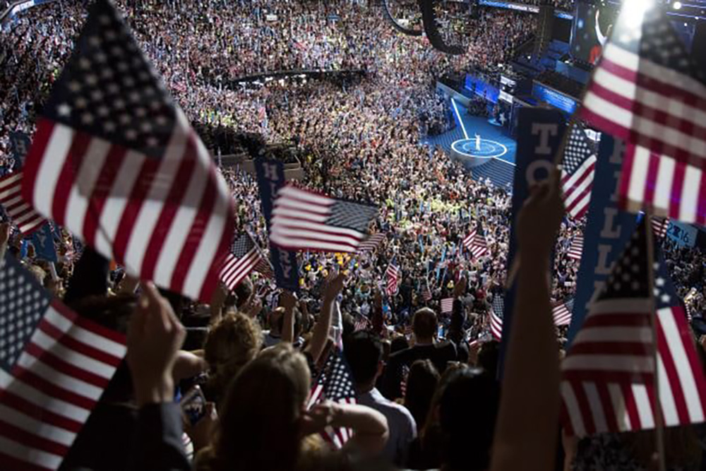 A large audience holding American flags