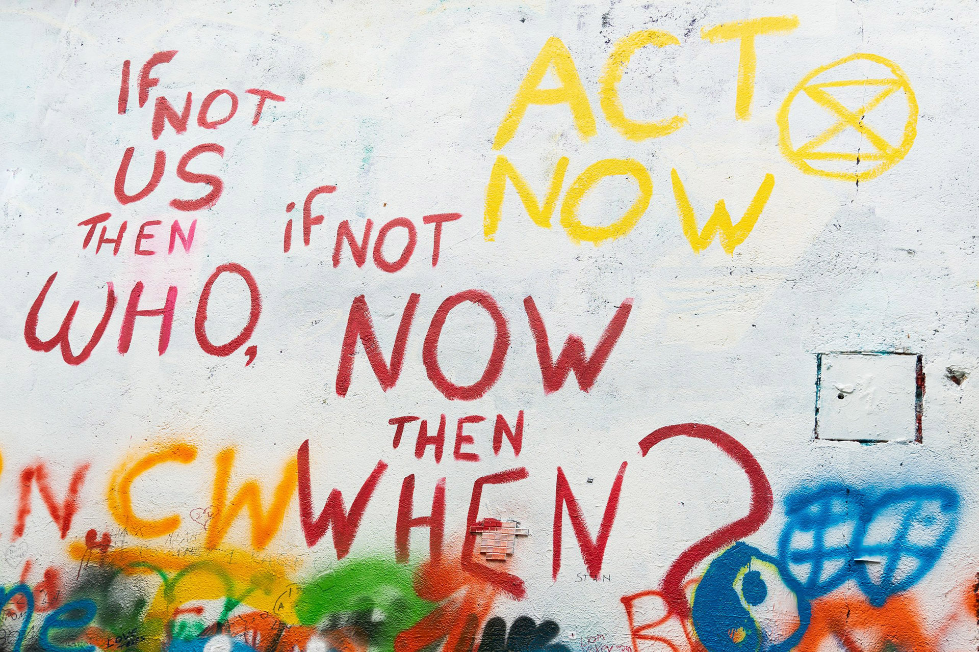 Graffiti reads: If not us then who, if not now then when. Act now.